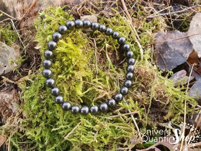 shungite bracelet pierre noire naturelle de russie 6mm posé sur de la mousse en forêt