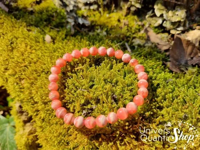 pierre rose rhodochrosite bracelet 6mm posé sur de la mousse verte en nature