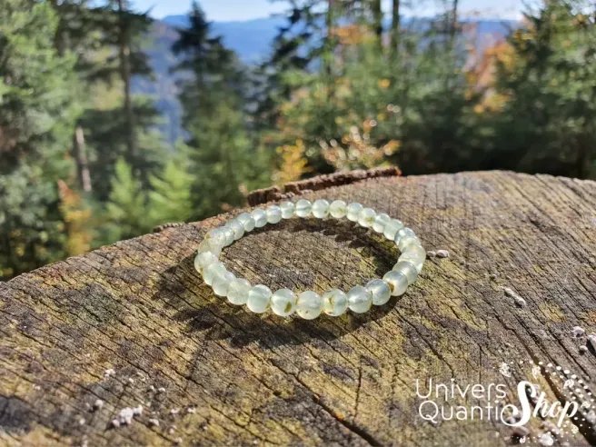 préhnite bracelet pierre naturelle verte 6mm sur un rondin de bois avec sapin en paysage