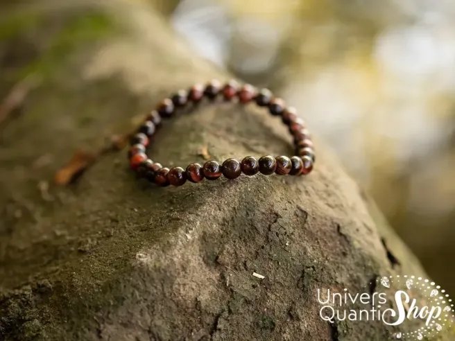 oeil de taureau bracelet pierre naturelle 06mm posé sur un rocher en forêt