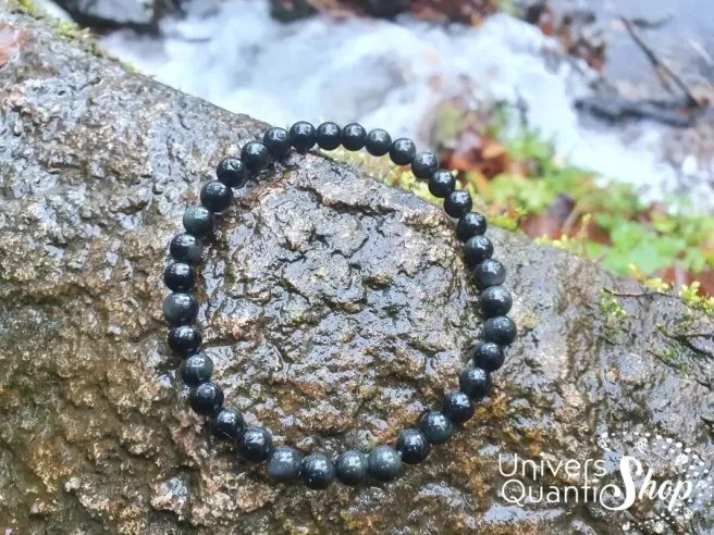 bracelet obsidienne oeil céleste pierre naturelle 6mm posé sur un rocher humide