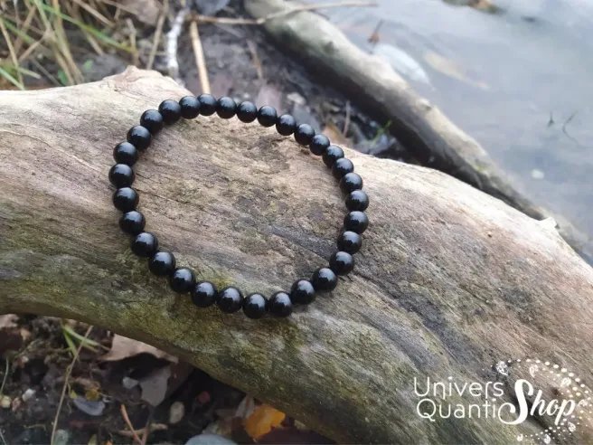 obsidienne noire bracelet pierre fine noire 6mm posé sur un arbre au bord de l'eau