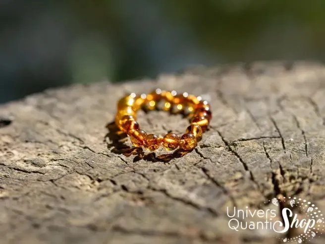 bracelet ambre bebe pour les dents cognac posé sur une souche d'arbre