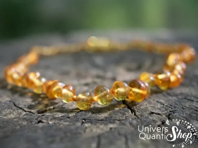 collier d'ambre bébé dent couleur jaune sur une souche d'arbre en nature