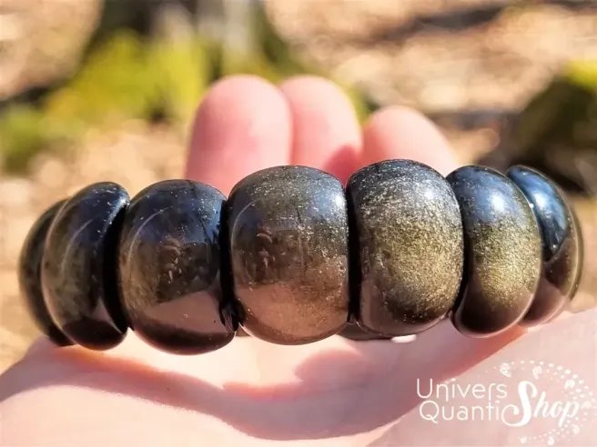 bracelet plat en obsidienne dorée posé dans une main qualité A+