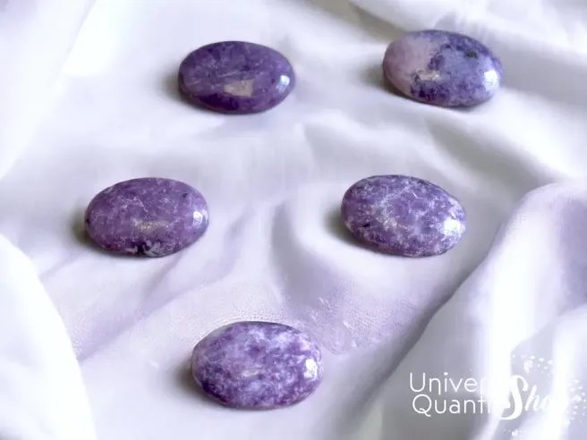 lépidolite, galet en pierre lépidolite violet qualité A+ posé sur un tissu blanc