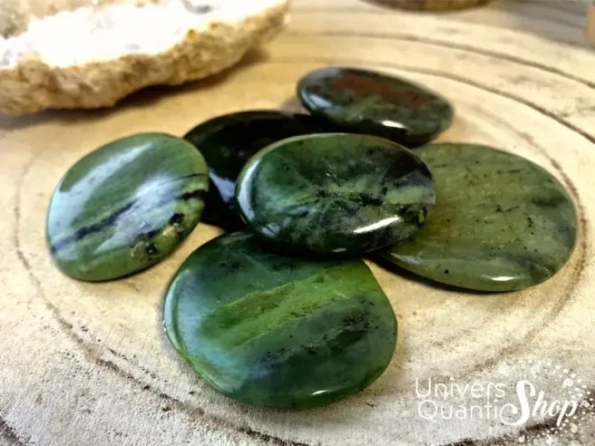 jade néphrite pierre plate verte porte bonheur posé sur un support en bois
