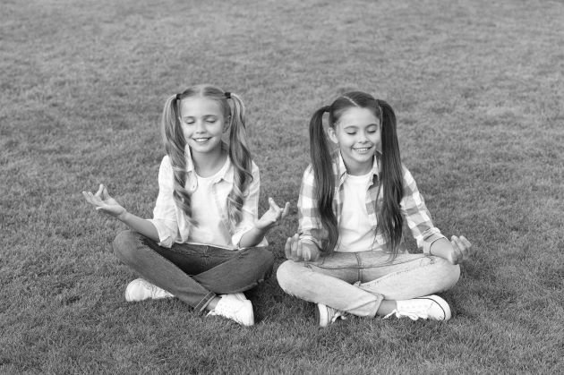 Enfants apprenant à méditer dans un parc, photo noir et blanc.