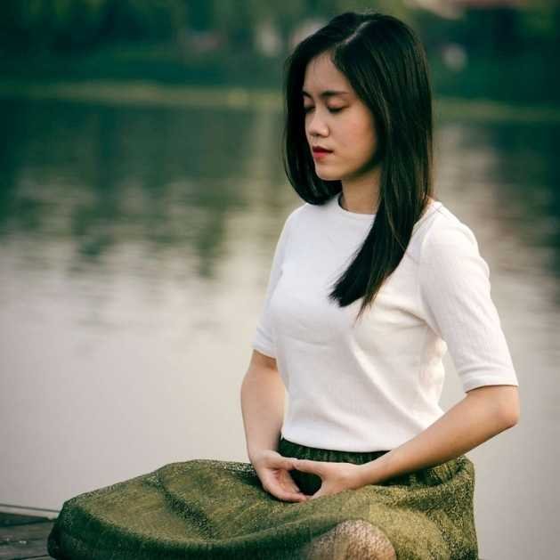 Femme qui médite au bord d'un lac en lotus. Premiers pas en méditation