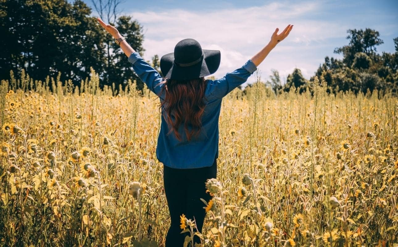 femme levant les bras dans la nature promenade pour pratiquer la gratitude