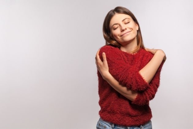 photo d'une femme en pull rouge sur fond gris estime de soi