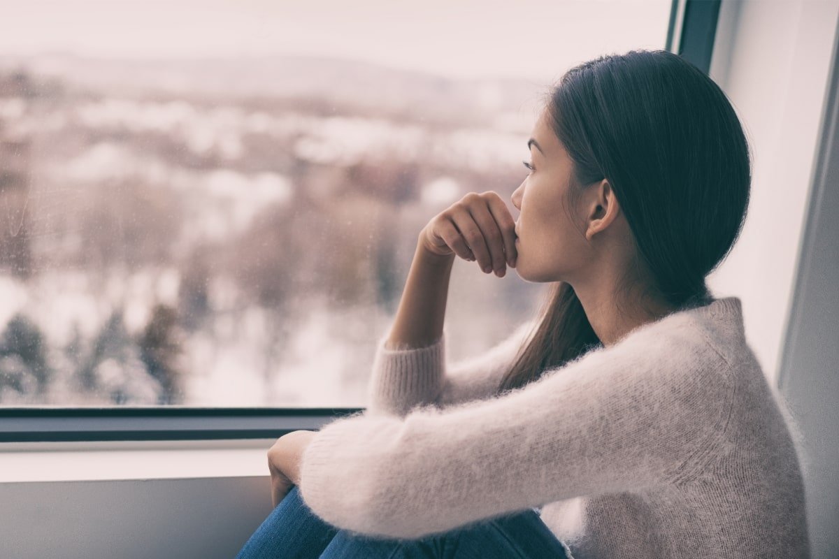 femme triste devant fenetre en hiver depression hivernale