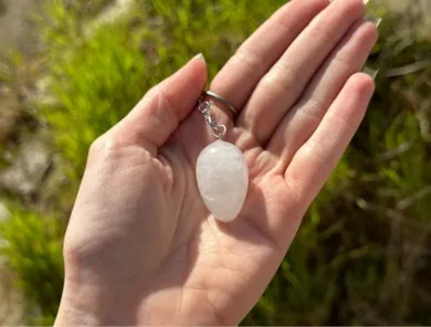 pendule cristal de roche oeuf posé dans une main dans la nature