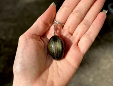 pendule obsidienne dorée en forme d'oeuf dans une main