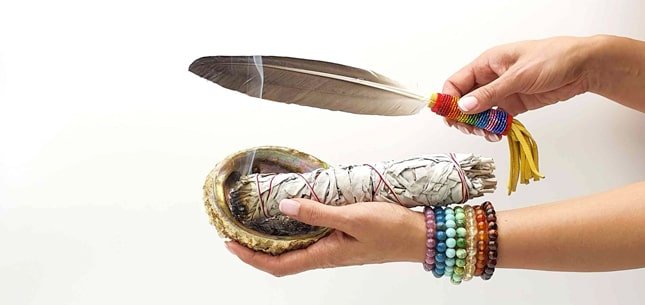 coquille d'ormeau avec une sauge blanche et une plume sauvage sur une bras et des minéraux en pierres naturelles 